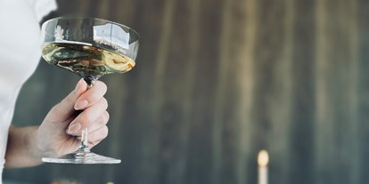 Hochzeit - Umgebung: in den Bergen - Pongau - Braut mit Champagner am Brauttisch - deck7