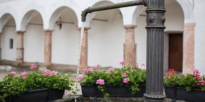 Hochzeit - Geeignet für: Filmproduktionen - PLZ 4816 (Österreich) - Blühende Sommerblumen am plätschernden Brunnen im Schlosshof.  - Landschloss Parz