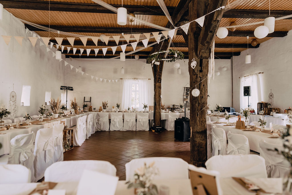 Hochzeit: Unser ehemaliger Kornspeicher als Feier-Scheune verbindet in perfekter Harmonie historischen Charme mit moderner Funktionalität. Seine sichtbaren Holzbalken und die rustikalen Steinmauern erzählen von einer langen Geschichte, während das offene Raumkonzept und die moderne Beleuchtung ein einladendes Ambiente für Ihre Feierlichkeiten schaffen. Große Fenster lassen natürliches Licht herein und gewähren einen atemberaubenden Blick auf das umliegende Burggelände. Mit Platz für die Hochzeitstafel oder gemütliche Sitzecken, Tanzfläche, Band oder DJ bietet der Kornspeicher den idealen Rahmen für unvergessliche Festivitäten. Eine Location, die den rustikalen Charme vergangener Zeiten mit der Freude des Feierns vereint. - Wasserburg Turow