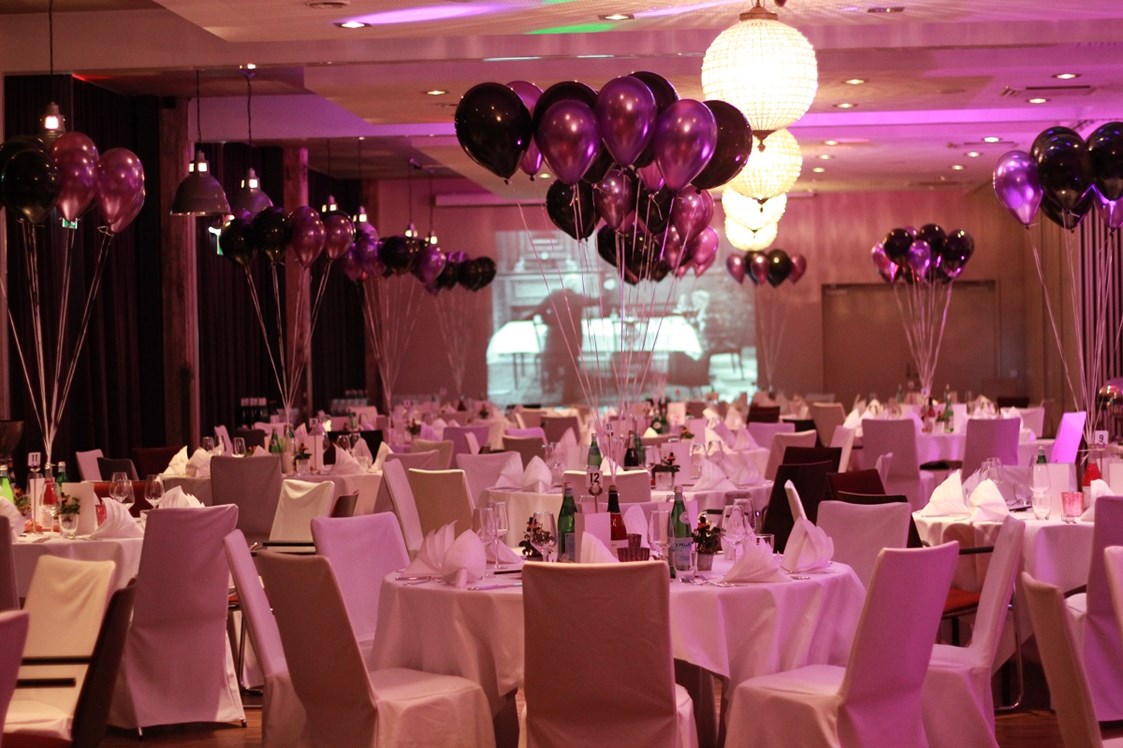 Hochzeit: Runde Tische bestuhlt mit Hussen und farblich abgestimmten Ballons - Hotel Altes Stahlwerk