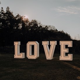 Hochzeit: XXL-Leuchtbuchstaben "LOVE" als Fotohintergrund/Dekoelement - Eventlocation am Wald