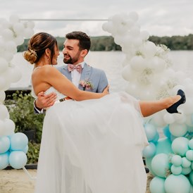Hochzeit: Ein glückliches Paar nach der freien Trauung auf unserem Tiny Beach mit einer festlichen Ballon Dekoration im Hintergrund - Richtershorn am See