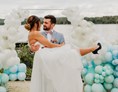 Hochzeit: Ein glückliches Paar nach der freien Trauung auf unserem Tiny Beach mit einer festlichen Ballon Dekoration im Hintergrund - Richtershorn am See