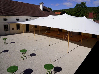 Hochzeit - PLZ 9155 (Österreich) - Innenhof der Alten Meierei Bleiburg mit weißem Festzelt / Zeltüberdachung ohne Seitenwände und grünen Stehtischen. - ALTE MEIEREI BLEIBURG