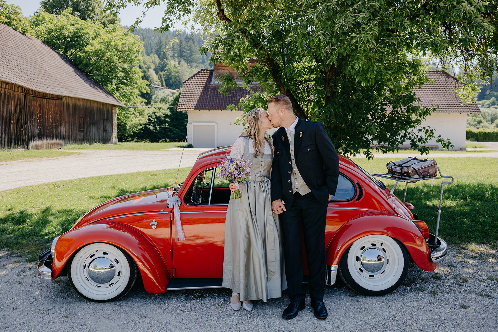 Hochzeitslocation: Paar mit rotem VW Käfer, Wirtschaftsgebäude hinter der Meierei. - ALTE MEIEREI BLEIBURG