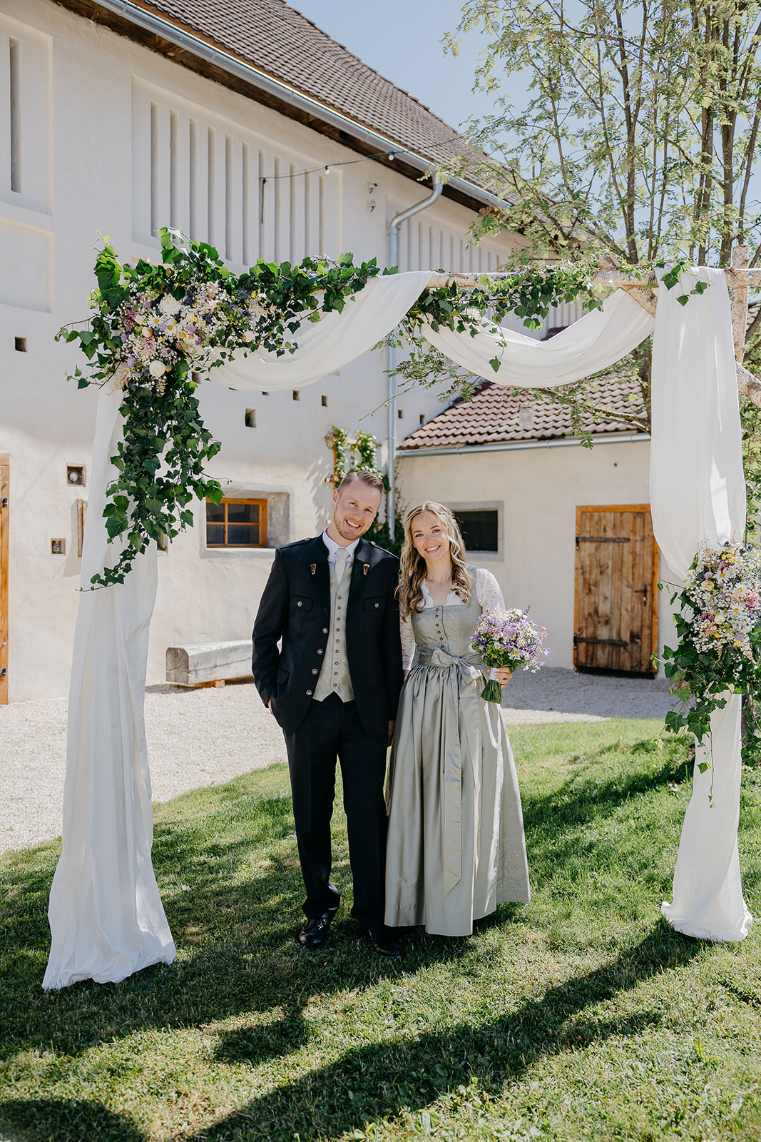 Hochzeitslocation: Paar unter Brautbogen im Innenhof der Alten Meierei. - ALTE MEIEREI BLEIBURG
