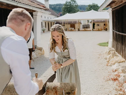 Hochzeit - PLZ 9155 (Österreich) - Brautpaar zersägt Holzbloch im Eingang zur Alten Meierei, im Hintergrund Festzelt im Innenhof.  - ALTE MEIEREI BLEIBURG