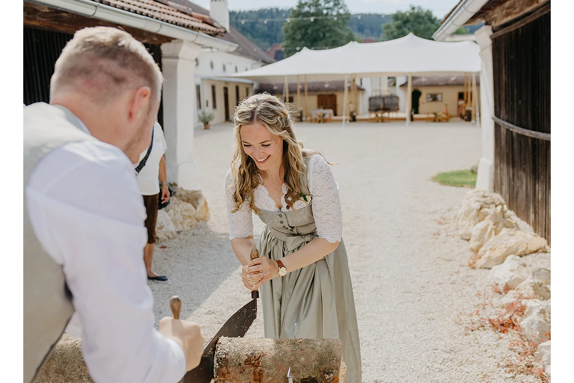 Hochzeit: Brautpaar zersägt Holzbloch im Eingang zur Alten Meierei, im Hintergrund Festzelt im Innenhof.  - ALTE MEIEREI BLEIBURG