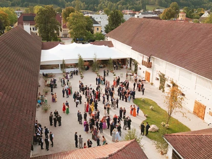 Hochzeit - PLZ 9155 (Österreich) - Drohnenaufnahme von Hochzeitsgesellschaft im Innenhof der Alten Meierei Bleiburg vor dem Festzelt - ALTE MEIEREI BLEIBURG