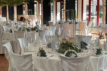 Hochzeit: Unsere Kutscher Remise mit  eingedeckten runde Tischen, eleganten Stuhlhussen unter  Birkenbäumen. - Jägerhof Biblis