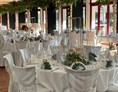 Hochzeit: Unsere Kutscher Remise mit  eingedeckten runde Tischen, eleganten Stuhlhussen unter  Birkenbäumen. - Jägerhof Biblis
