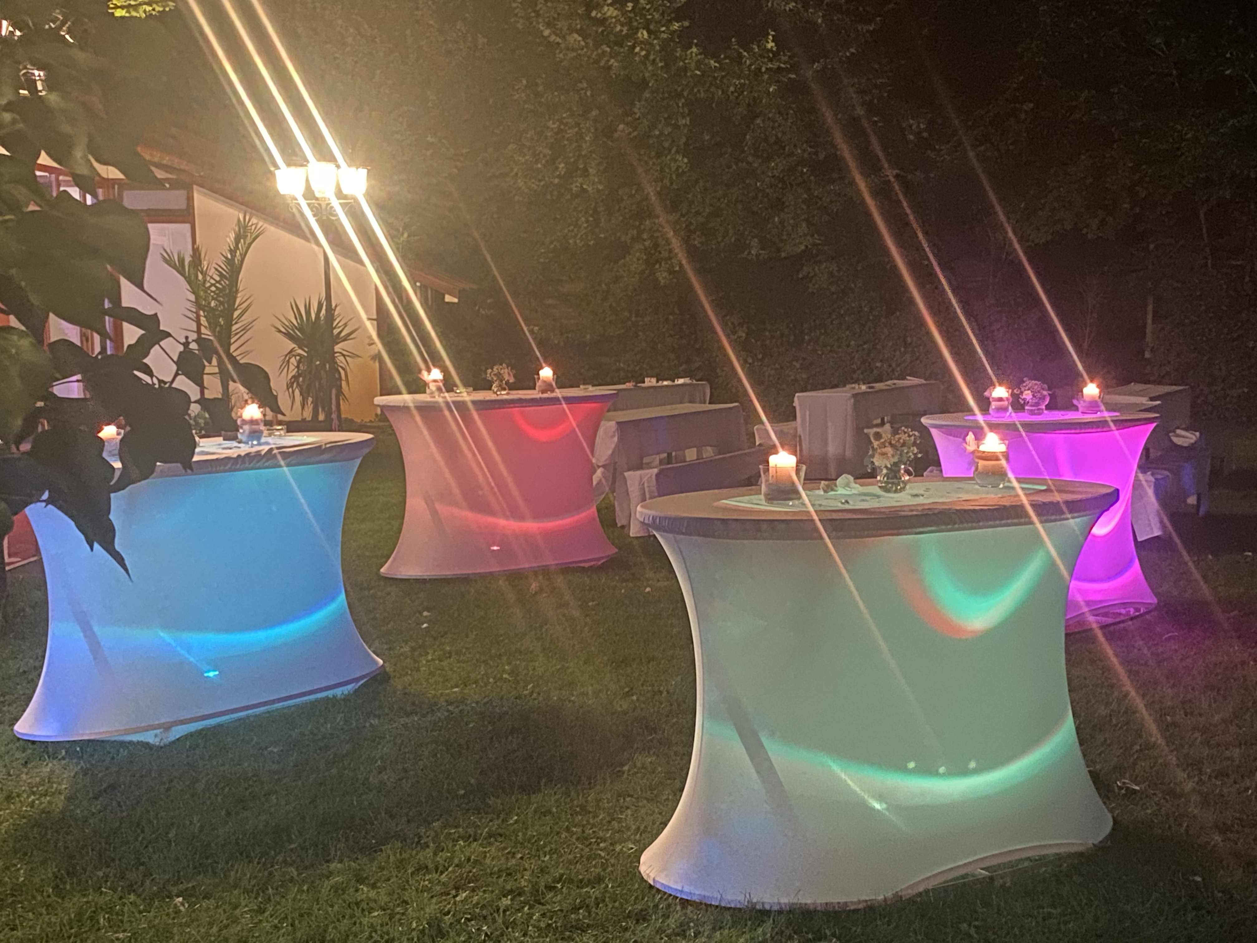 Hochzeitslocation: Beleuchtete ovale Stehtische
in einer lauen Sommernacht. - Jägerhof Biblis