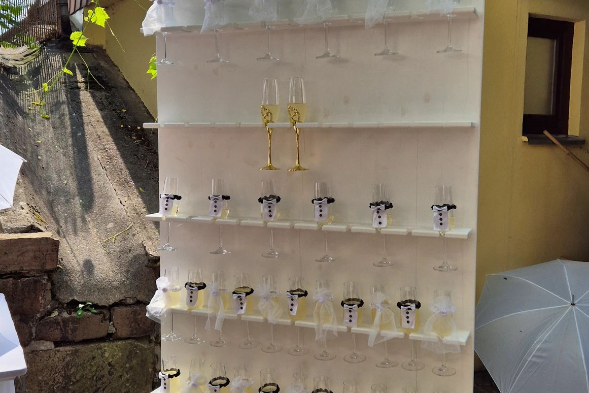 Hochzeitslocation: Stilvoll dekorierte Sektwand beim Hochzeitsempfang im Wanderheim Germersheim. Die goldfarbenen Gläser, floralen Akzente und das warme Licht schaffen eine festliche Atmosphäre und bieten einen glamourösen Auftakt für jede Feier. Ideal als Fotospot und Empfangsbereich für Brautpaare, die ihren Gästen einen eleganten, modernen Start in den Hochzeitstag bieten möchten. - Wanderheim Germersheim