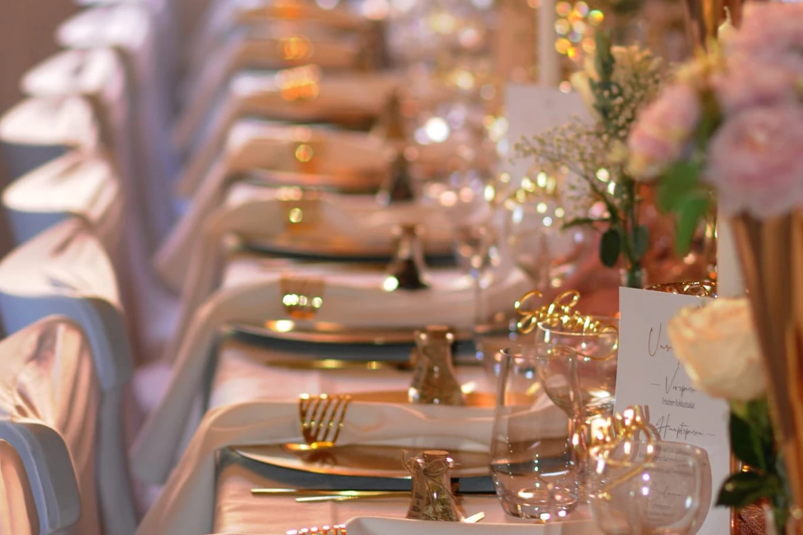 Hochzeitslocation: Lange Tafel mit goldenen Tellern und Rosé-Blumenschmuck – eleganter Stil für exklusive Feiern. - Wanderheim Germersheim
