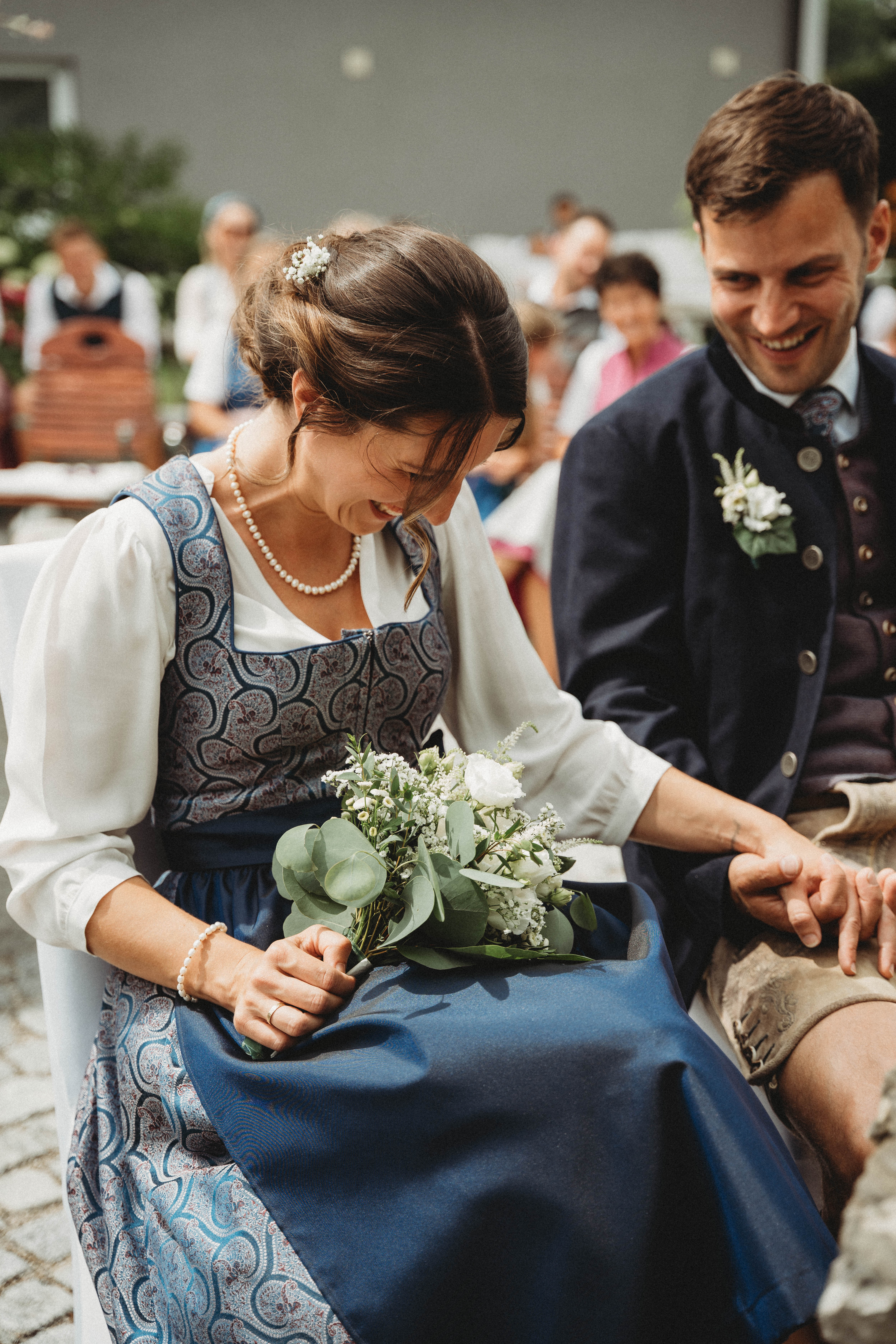 Hochzeitslocation: Brautpaar lacht gemeinsam während der standesamtlichen Trauung im Freien bei einer emotionalen Sommerhochzeit in Österreich. Authentischer Hochzeitsmoment voller Freude und Leichtigkeit in stilvoller Hochzeitslocation PATRIX mit romantischer Atmosphäre und persönlicher Zeremonie. - PATRIX Hotel | Restaurant | Bar
