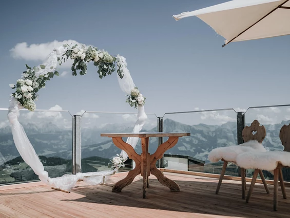 Brautpaar feiert Hochzeit auf der Terrasse der Kaiserlounge Ellmau mit Alpenblick und elegantem Ambiente. Hochzeit in der Kaiserlounge Ellmau – Feiern mit Blick auf den Wilder Kaiser