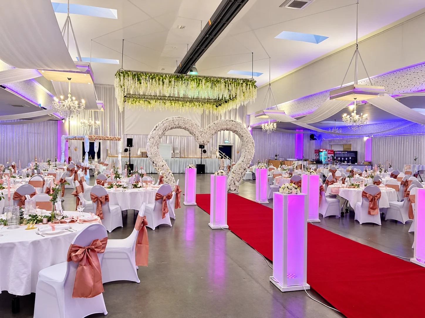 Hochzeitslocation: Hochzeitsgang mit rotem Teppich und Blumenherz - Metadrom Eventcenter